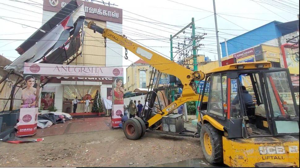 புயல் காற்றில் சரிந்த ராட்சத பேனர்; ஆபத்தான முறையில் பணியில் ஈடுபட்ட JCB ஊழியர்!